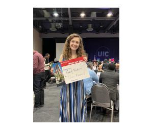 Megan Helms in an event space holding a sign stating she matched into family medicine at Illinois Masonic